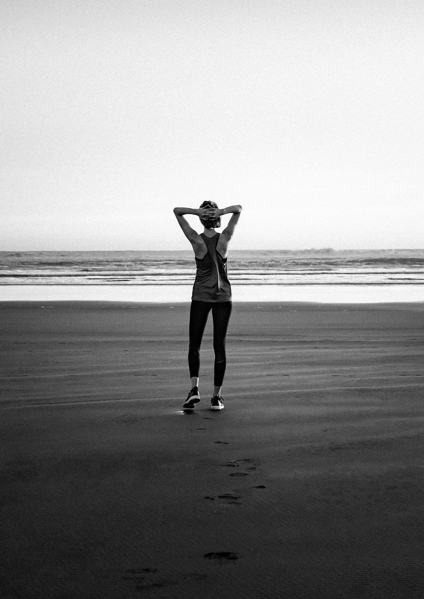 women standing on the beach, hands behind her head